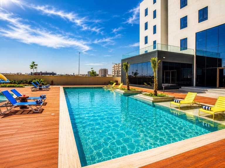 The swimming pool and its terrace under a clear sky, with the hotel on the right